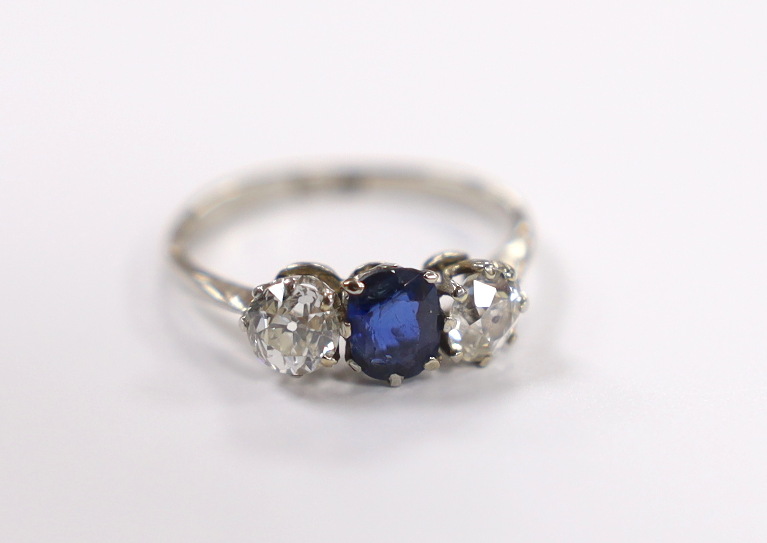 An early to mid 20th century white metal (stamped plat), single stone sapphire and two stone diamond set ring, size M, gross weight 2.7 grams.